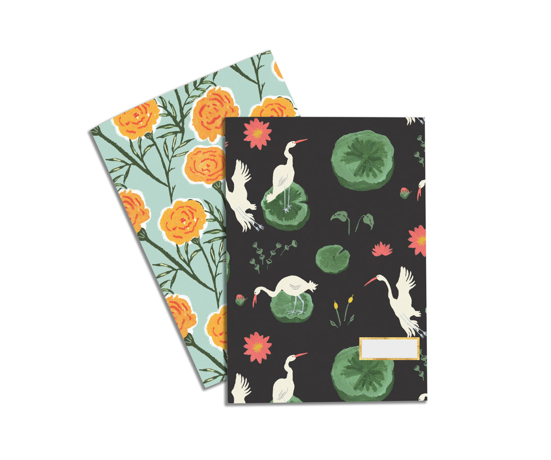 Illustrated Notebook Set by Atelier Mave with one design being a beautiful pattern of white swans on a lake and the other design being a pattern of lovely orange marigolds.