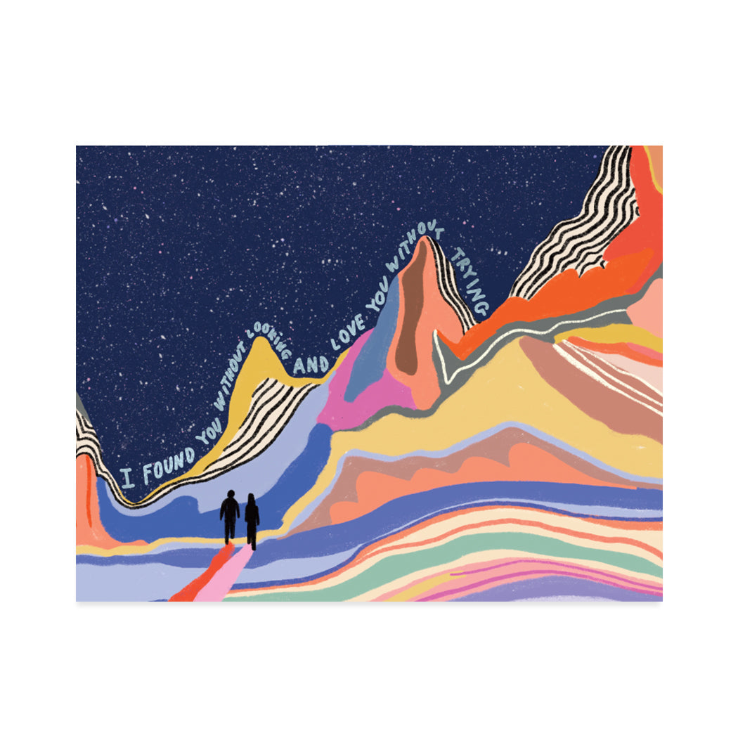 Greeting card designed by Marina Castaldo. A lovely illustration of two silhouettes on a colourful mountainous landscape with a silver foil sentiment that reads, "I found you without looking and love you without trying".