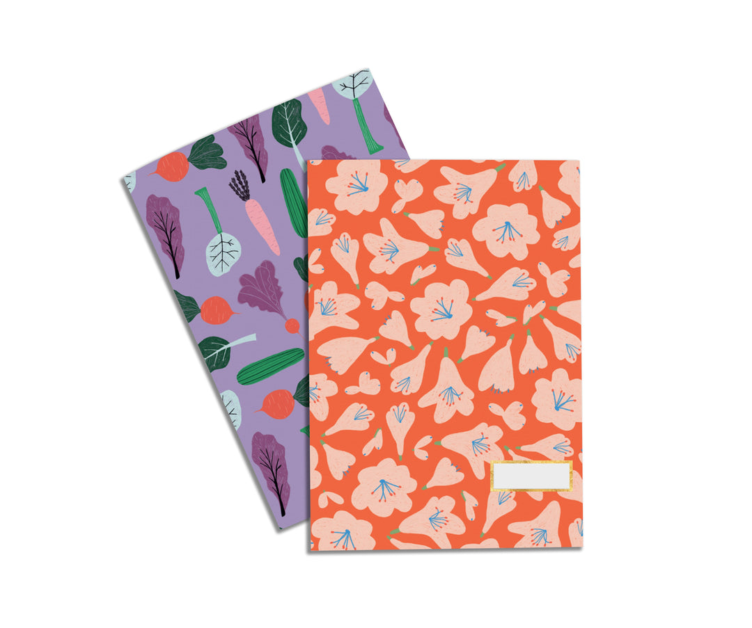 Illustrated Notebook Set by Crissie Rodda with one design being a pattern of orange florals and the other design being a variety of root vegetables in orange, purples, and greens. 