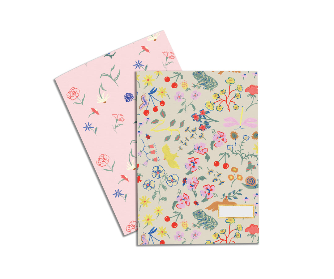 Illustrated Notebook Set by Atelier Mave with one design displaying a group of wildflowers and the other being a dainty floral pattern with a light pink background.