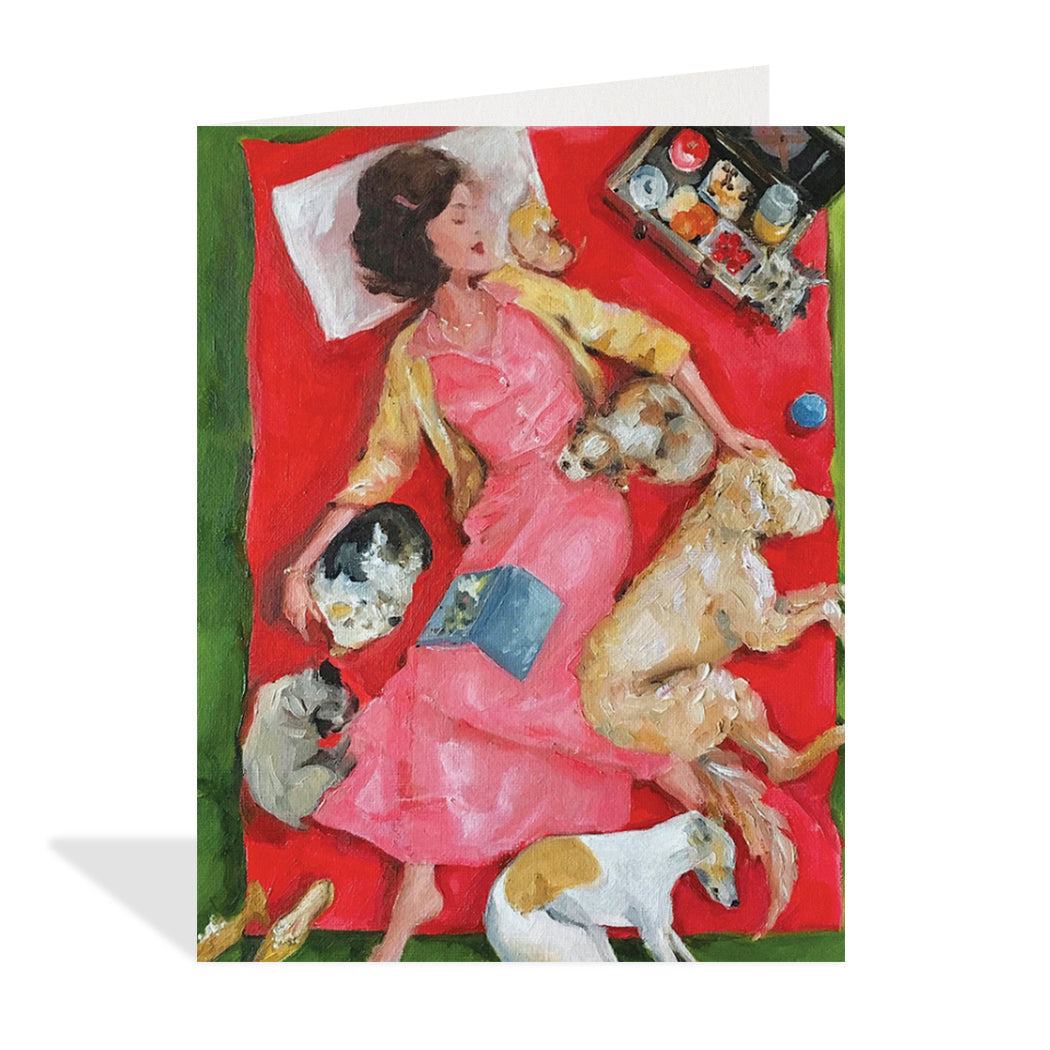 Greeting card design by Canadian Artist, Lisa Finch. An elegant painting of a woman laying down on a bed, surrounded by puppies and dogs with a book open on her lap and an open picnic box.