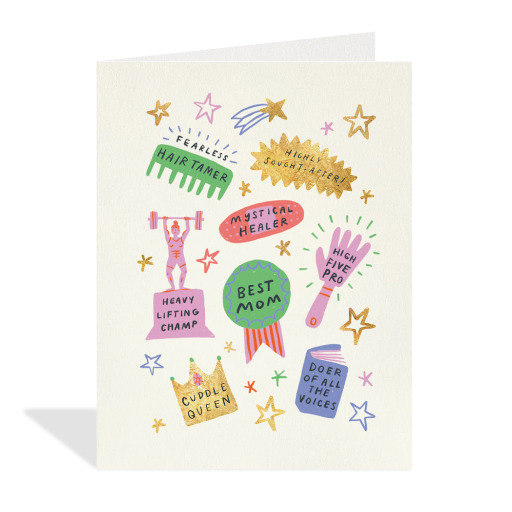 Greeting card design by Emily Doliner. A colourful illustration of awards, ribbons, stars, a book and a crown with sentiments that read "hair tamer, mystical healer, highly sought-after, cuddle queen, best mom, and heavy lifting champ".
