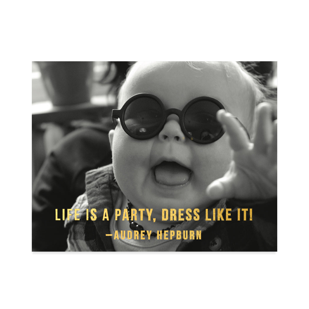 Black and white, close-up photographic greeting card of a baby wearing large sunglasses. Gold foil typography that reads "Life is a party, dress like it! - Audrey Hepburn".