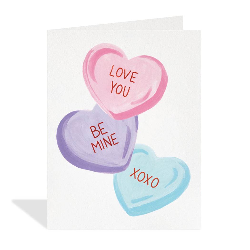 Greeting card design by Canadian Artist, Paige & Willow. A fun illustration of three candy conversation hearts with red foil sentiments that read "Love you, miss you, and xoxo".